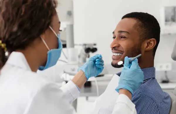 Patient sitting in dental chair smiling at dentist.