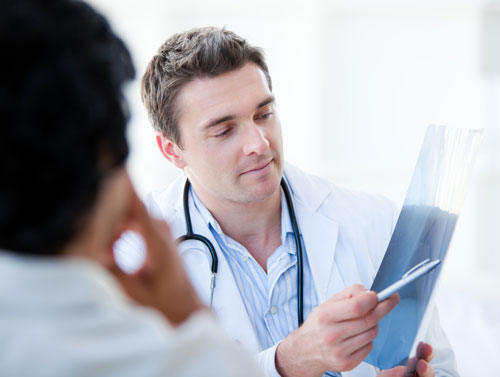 Dentist discussing Bone Growth Factors while reviewing x-ray with patient. Learn more about dental implants at Solutions Dental Implants in Sun City AZ
