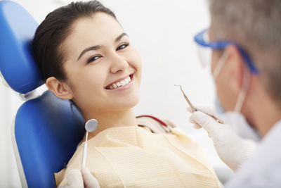 Woman smiling in a dentist chair before gum surgery at Solutions Dental Implants in Sun City West, AZ